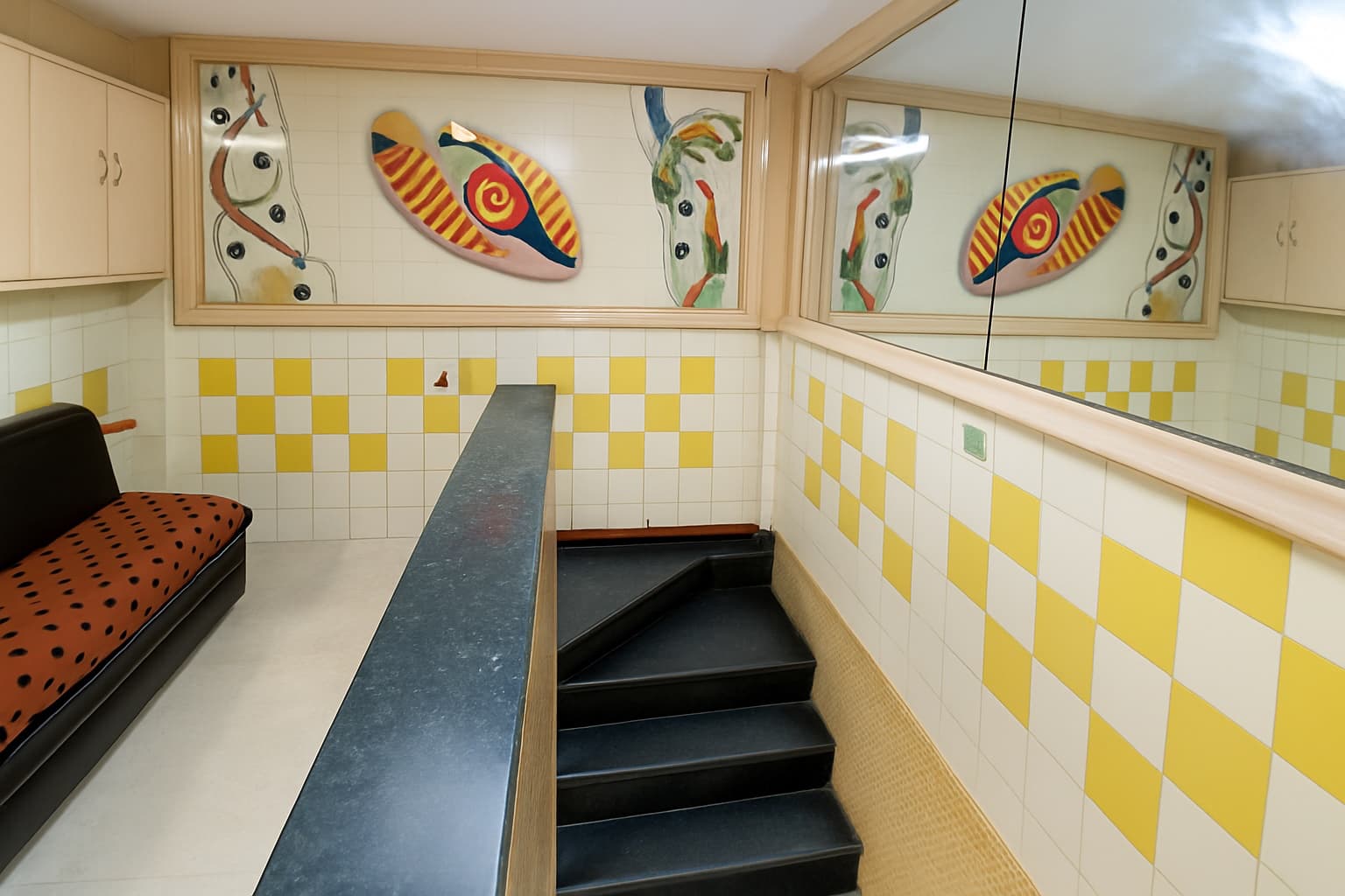 Lobby seating beside the staircase, with mosaic wall art